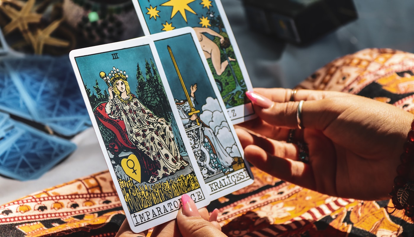 Manos sosteniendo las cartas de La Emperatriz y la Reina de Espadas durante una consulta